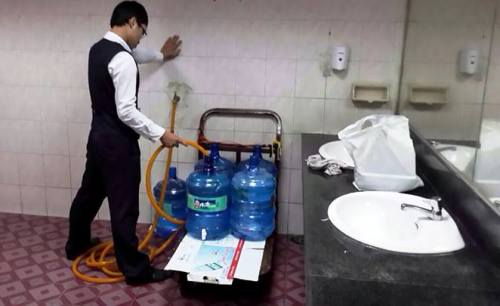 Nam nhân viên cho nước từ nhà vệ sinh vào bình nước